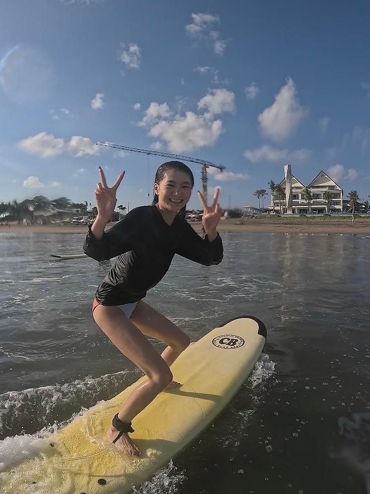 A student on a yellow board throwing peace signs at the camera